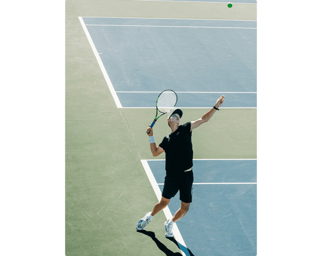 A tennis player on hardcourt is about to hit a serve.